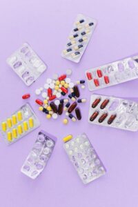 Assorted tablets and capsules arranged on a purple surface, representing various medications.