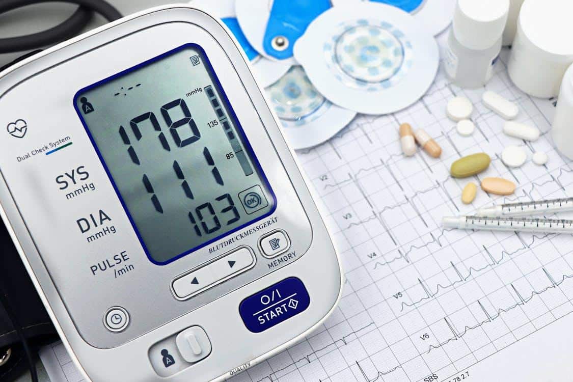 Digital blood pressure monitor with an ECG printout alongside medicine bottles