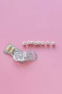 White letter tiles spelling “diabetes” on a pink background with various medications placed nearby.