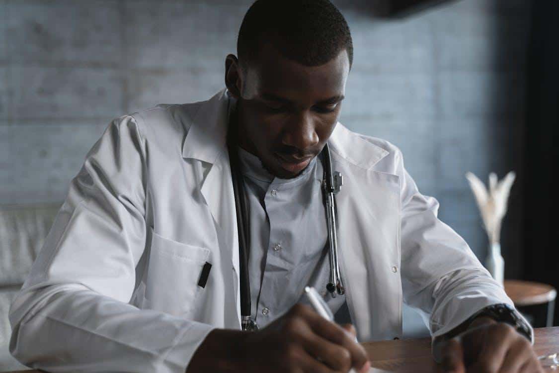 A doctor focused on writing detailed notes on a medical document.