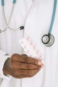 Doctor holding a medication pill in hand, representing prescription guidance and patient treatment planning.