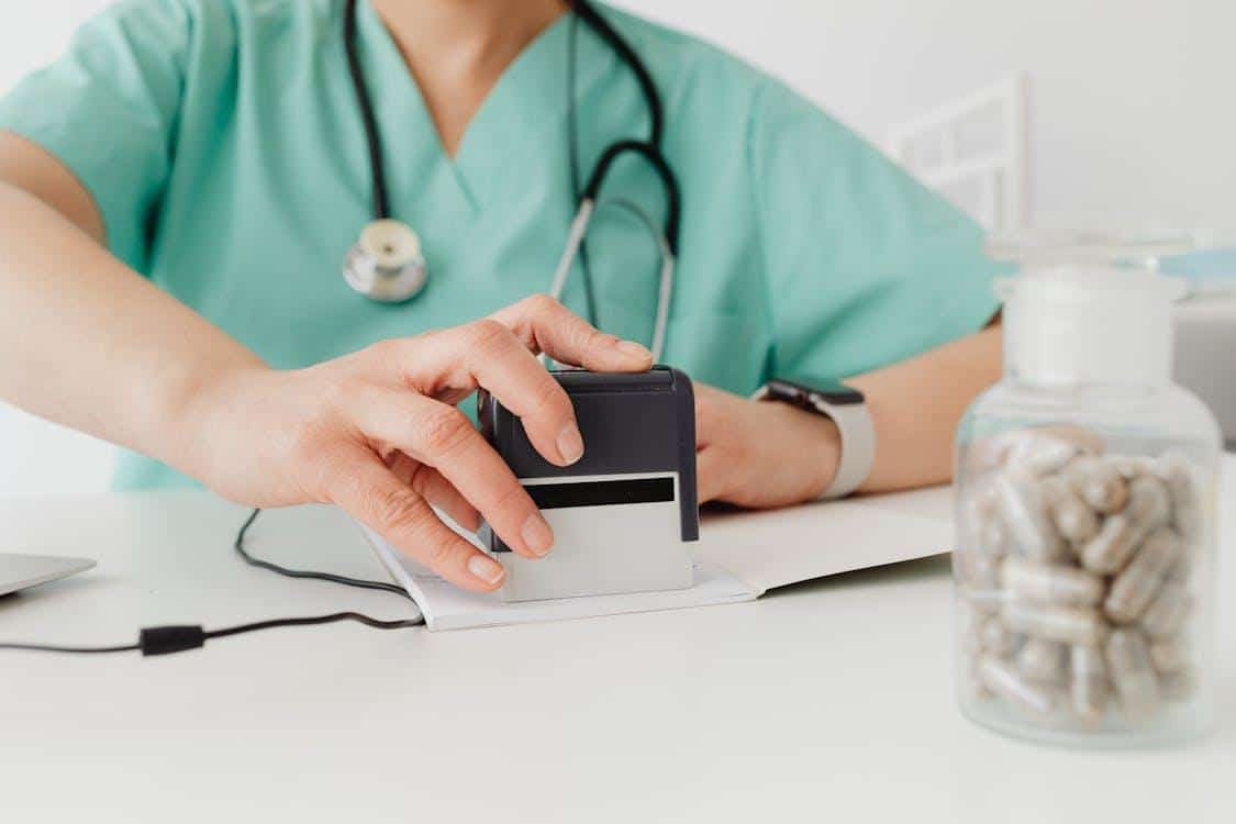 Doctor stamping a prescription document, finalizing approval for patient medication.