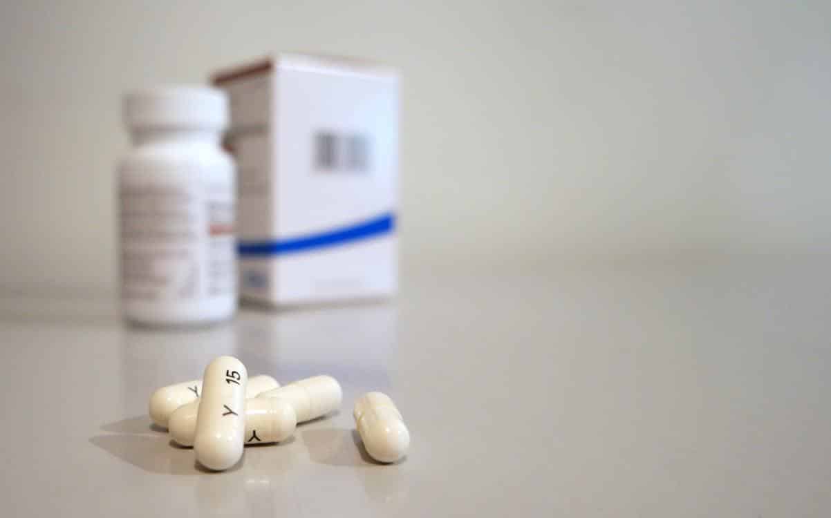 Five white oblong medication pills arranged in a row on a clean, neutral surface, representing a daily dosing schedule.