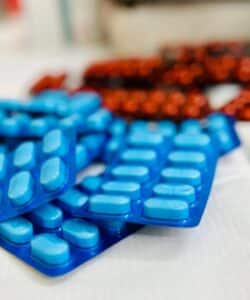 A top-down close-up view of blue and red medicine blister packs arranged on a clean surface.