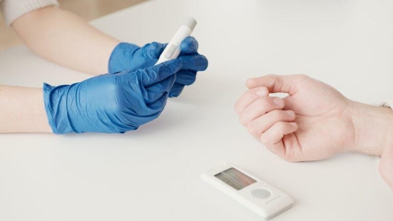 Healthcare worker using a glucometer to check a patient’s blood sugar level