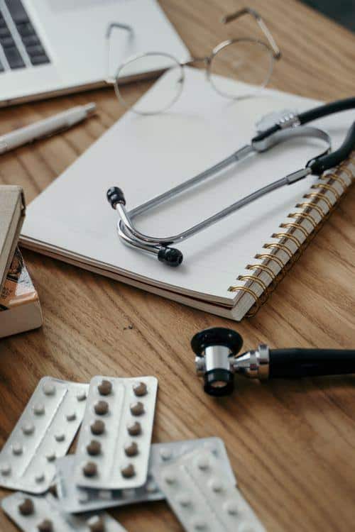 Stethoscope, prescription pills, and notebook on a doctor's desk