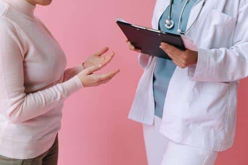 Patient consulting with a doctor holding a clipboard