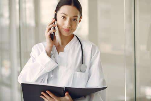 Doctor holding a notepad while speaking on the phone.