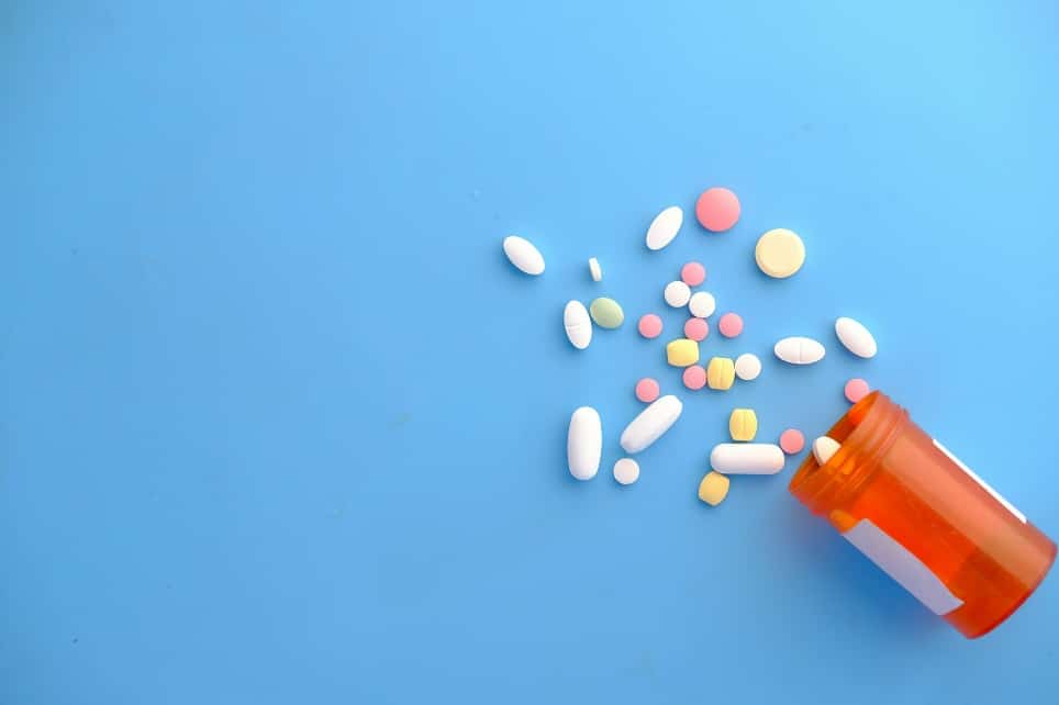 Prescription bottle with pills spilled on a table