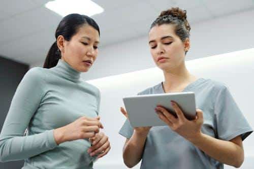 Patient reviewing digital medical records on a tablet with a healthcare staff.