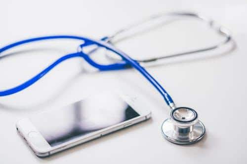 Stethoscope placed beside a smartphone showing a telehealth consultation