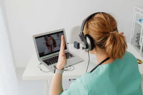 Woman attending a telehealth consultation with her doctor through a video call on a laptop.