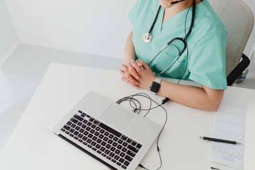 A doctor conducting a virtual telehealth consultation on a laptop