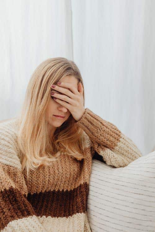 Woman covering her face, showing fatigue and low energy symptoms
